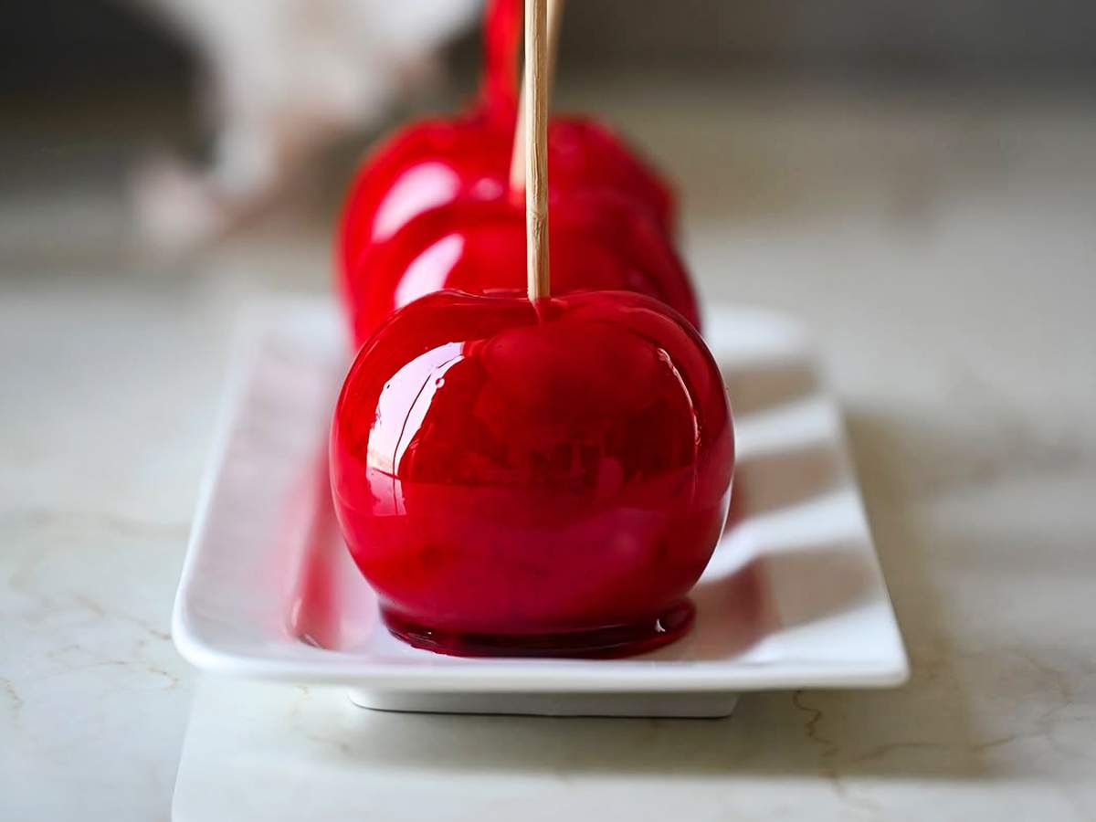 ilustração de varias maças caramelizadas em uma calda de caramelo vermelho com um palito 